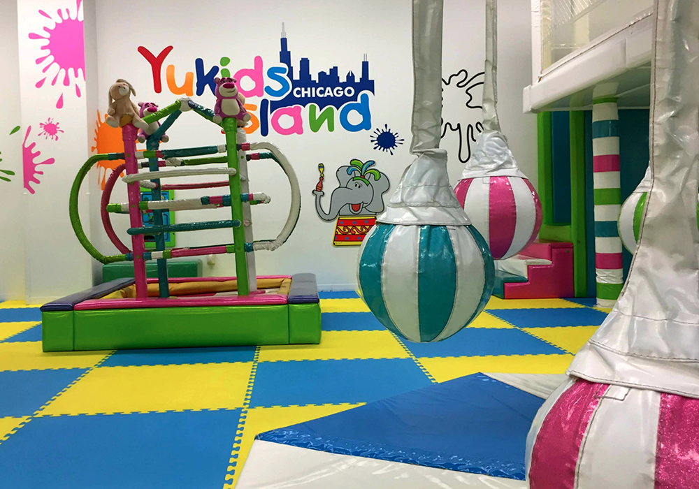 Yu Kids Island indoor play area in Schaumburg, Illinois, featuring colorful soft play structures, climbing frames, and swinging balls, offering a fun and safe environment for young children.
