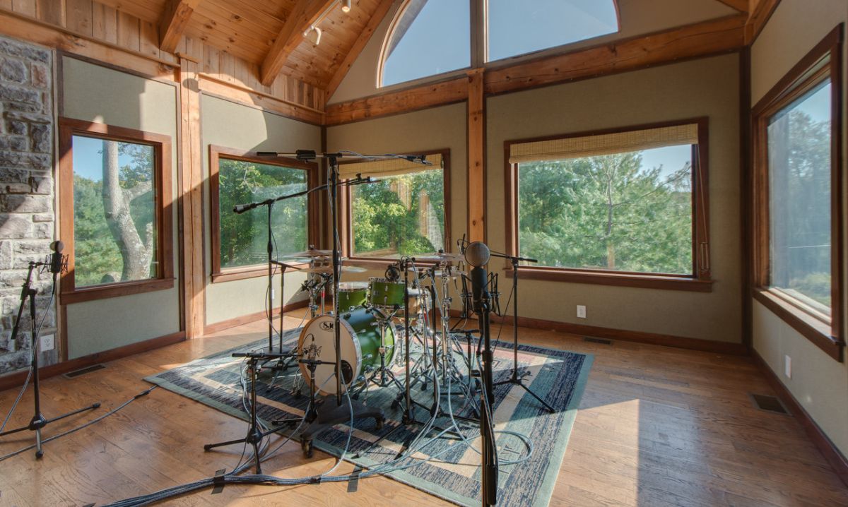 A professional recording studio at Dark Horse Recording in Franklin, Tennessee, featuring a drum set, microphones and large windows overlooking nature.